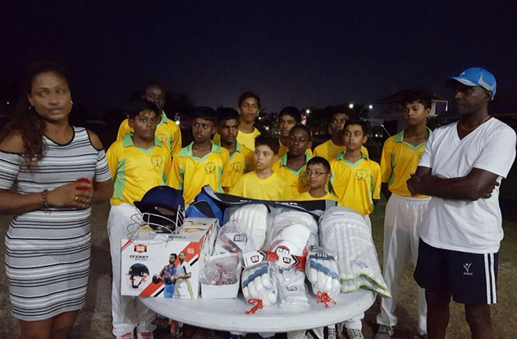 Everest Cricket Club executive member Juanita Mootoo (left), coach David Harper (right) and players of the club pose with the gear.