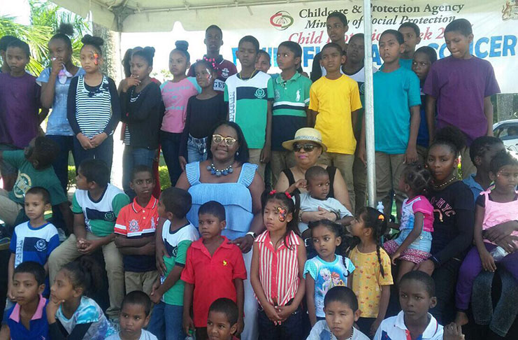 Minister of Social Protection Amna Ally and Minister with the Ministry of Natural Resources, Simona Broomes , with some of the children at the Family Fun Day