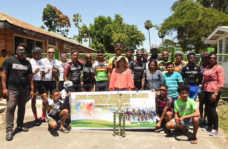Prize winners of the various categories in yesterday’s 80-mile Kadir Mohamed Memorial ‘Ounce of Gold’ Cycle Road Race strike a pose with Mrs. Mohamed (centre front) after receiving their prizes (Adrian Narine photo).