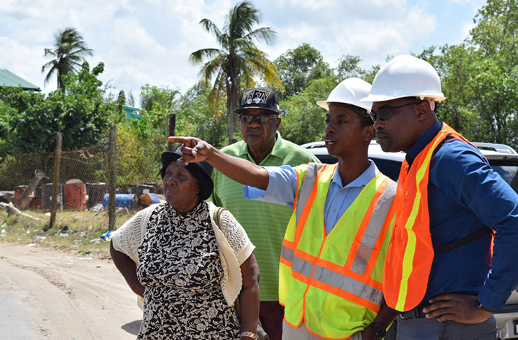 Minister of Public Infrastructure David Patterson inspecting road works with residents of New Amsterdam