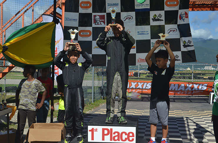 Justin Ten-Pow displays his trophy from the third step of the podium following one of the Micro Max Races in Jamaica.