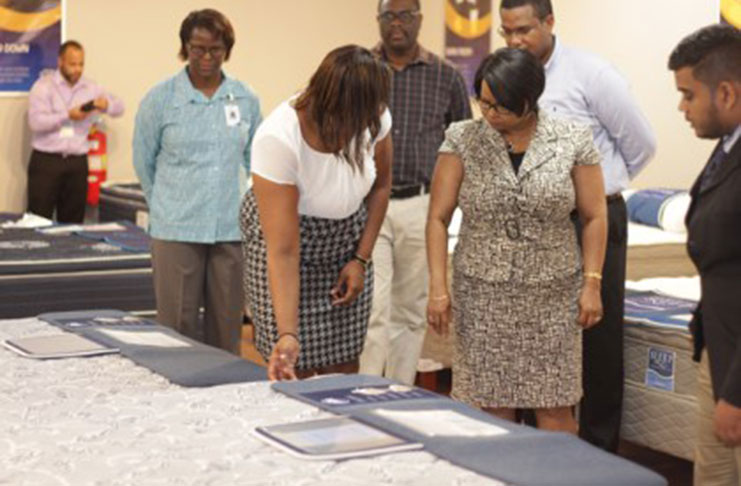 Kayeann Moore, Furniture Buying Manager, Courts Guyana Incorporated showing Minister of Public Health Volda Lawrence, some of the items offered at the Sleep Centre