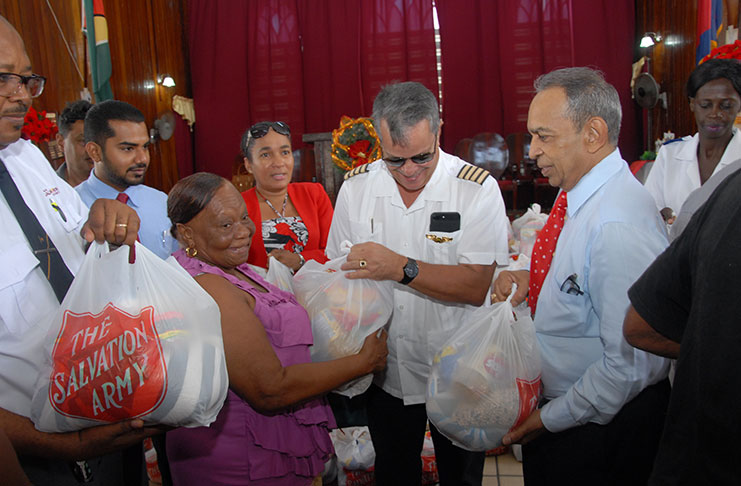 Chairman of the Salvation Army Advisory Board and the Private Sector Commission, Mr. Edward Boyer (right), along with Captain Gerald Gouveia and other representatives of the PSC attending to senior citizens at the Army’s Hampers Distribution Programme last Monday. At extreme left is Divisional Commander, Major Matignol Saint Lot