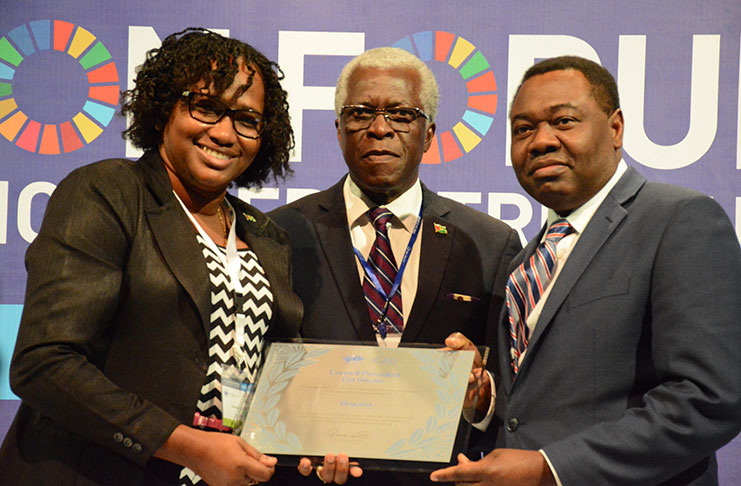 Minister within the Ministry of Public Infrastructure, Annette Ferguson and Director General of the GCAA, Lieutenant Colonel (retired) Egbert Field hold the award, along with President of the ICAO, Dr. Olumuyiwa Benard Aliu