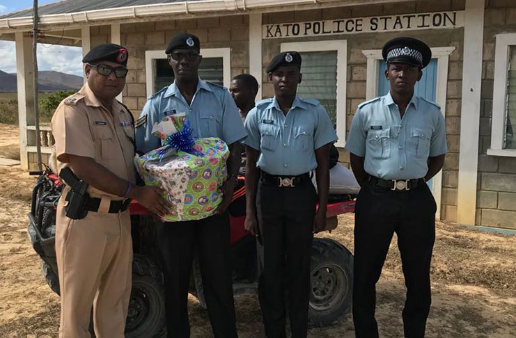 Commander Ravindradat Budhram presents a hamper to a policeman at Kato Police Station in the presence of his colleagues