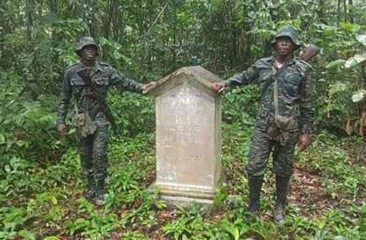 Two members of the GDF stand alongside  the Guyana-Venezuela boundary marker on Thursday.