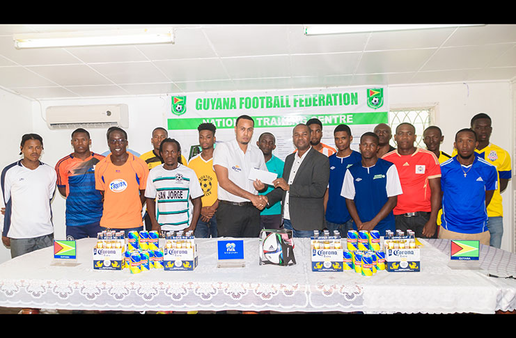 Top Brandz Distributors’ Marketing Manager Marvin Wray makes the presentation of the sponsor’s cheque to GFF president Wayne Forde, while some members of the participating teams look on. (Delano Williams photo)