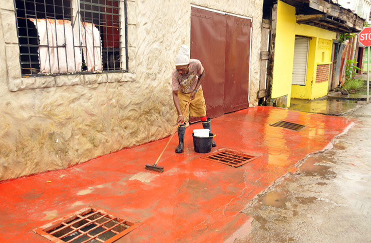An Albouystown resident cleaning up on Saturday after
the community was affected by flooding due to heavy
rains in recent days (Adrian Narine photo)