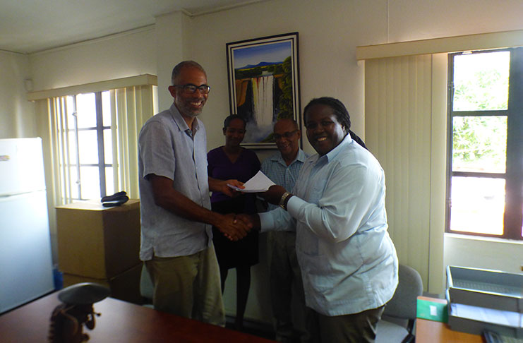 PS Joslyn McKenzie (right) presents the contract to TCG’s Timothy McIntosh in the presence of FCPF Project Coordinator Clayton Hall and Project Assistant Michelle Astwood