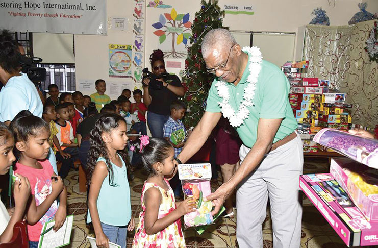 This child receives a toy from President David Granger as others look on (Ministry of the Presidency photo)