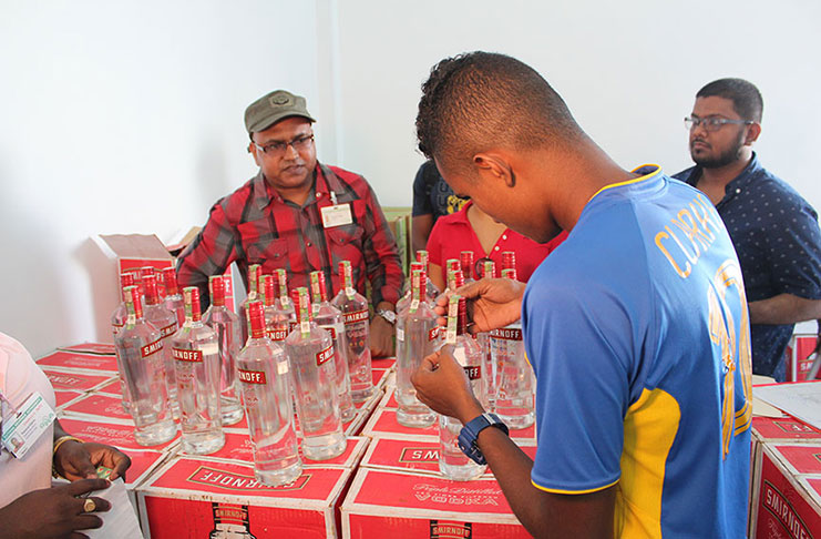 Retailers in Essequibo affixing Excise Stamps on importer liquor under the supervision of GRA Officers