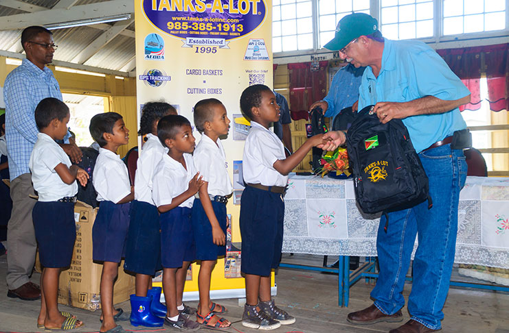 President of Tanks-a-lot Inc., Anthony Cannata, hands over the bags of supplies to the first set of Lusignan Primary School boys