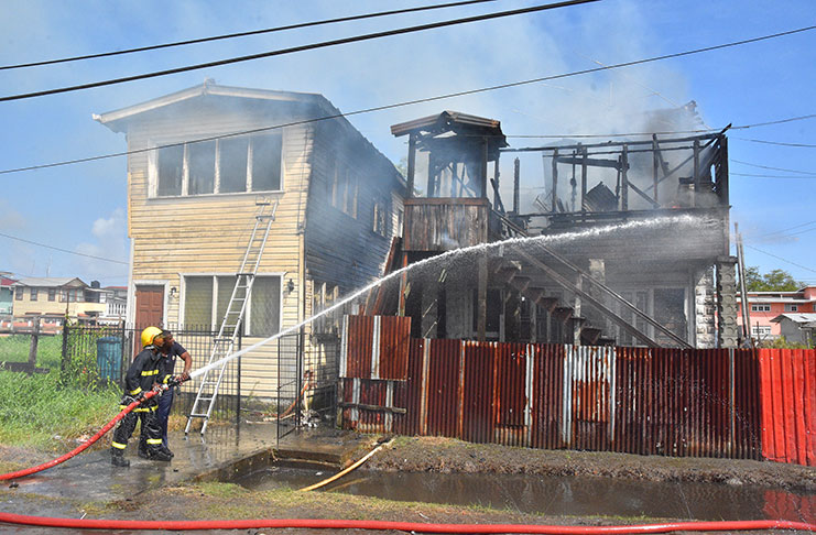 Firemen dousing the remaining flames with water from their truck