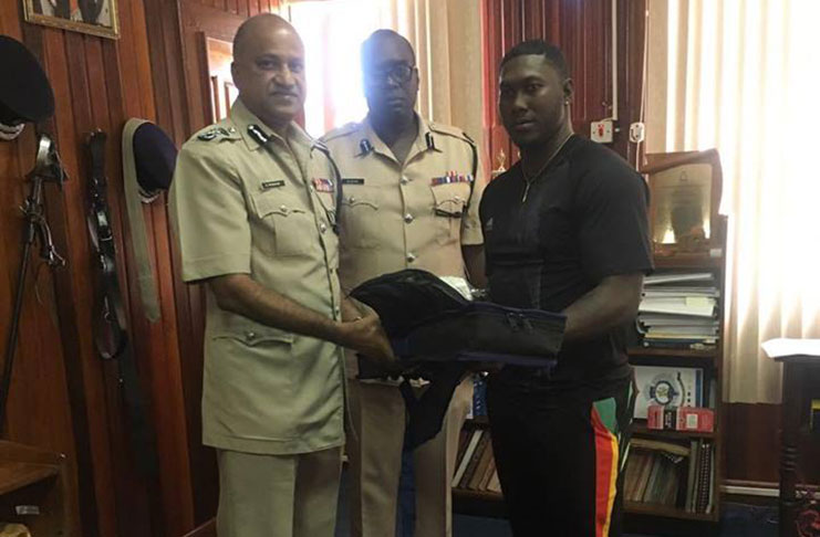 Commissioner of Police Seelall Persaud (right) makes a presentation to Ricardo Adams. Also in photo is Assistant Commissioner of Police Nigel Hoppie