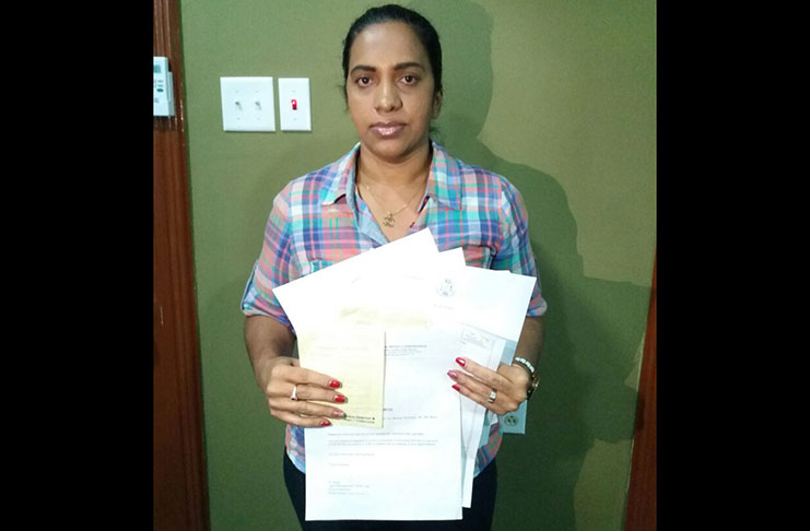 Rhonda Roberts holding up documents issued to her by GGMC, which state that she is the owner of the mining blocks in Oko, Cuyuni, District Four