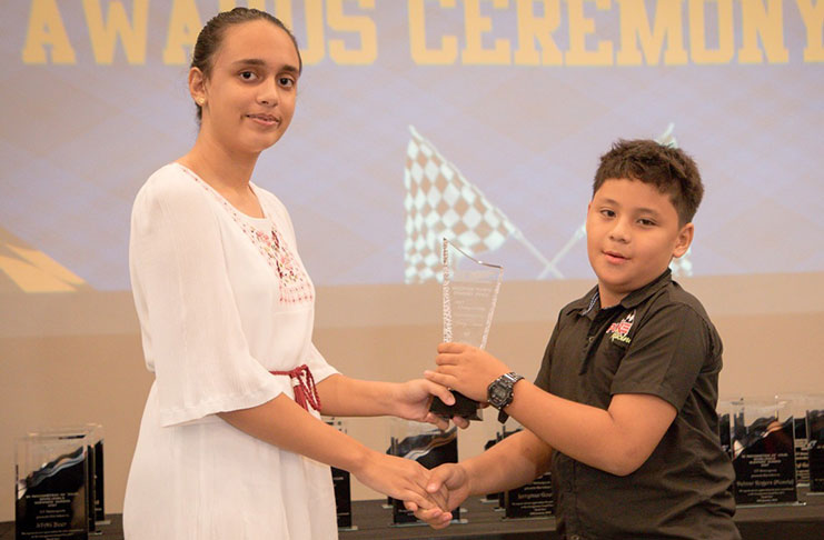 Pure Racing’s Jeremy Ten-Pow receives his championship trophy from Ms. Avasa Persaud.