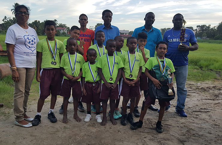 Diamond Upsetters FC U-11 players show off their Ralph Green/EBFA medals in the presence of club executives. The League's best goalkeeper, Joshua Dias, is at right with his trophy and backpack.