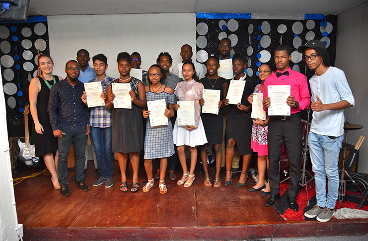 Twelve of the certified Associated Board of the Royal School of Music (ABRSM) students stand along with their Vocal teacher Ellenelle Gilliam (first left); Primary Guitar instructor and co-founder of Music Unlimited, Christian Sobers (second left); and Primary Keyboard instructor and co-founder of Music Unlimited, Jeremy Sobers (centre in second row)