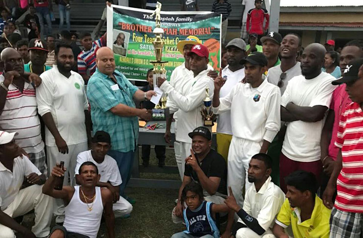 Mukesh Appiah (left) presents the trophy to captain of the winning team in the presence of jubilant players and spectators.