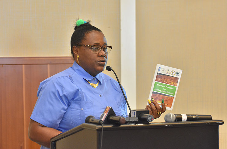 Minister within the Ministry of Natural Resources, Simona Broomes, holds up a “Code of Practice for Mining made simple” booklet on Tuesday (Samuel Maughn photo)