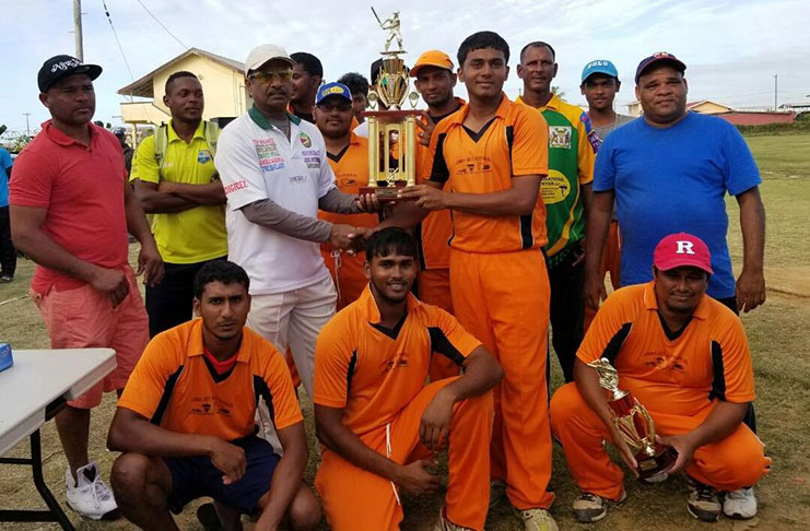 Steve Narine of GFSCA (left) hands over the trophy to Rajbance Hemraj, captain of the winning team in the presence of his team members.
