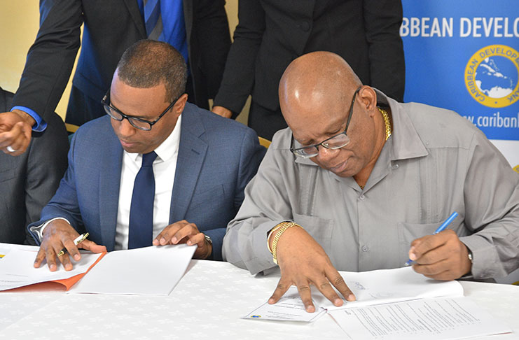 Director of the CDB’s Economics Department, Dr Justin Ram (left) and Minister of Finance, Winston Jordan, signing the grant agreement at Cara Lodge on Thursday (Samuel Maughn photo)