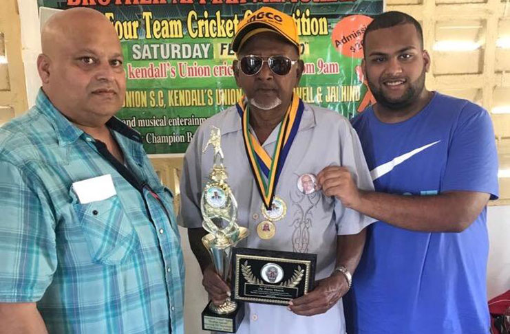 73-year-old Zamin Hamid proudly displays his token in the presence of Mukesh Appiah (left) and Matthew Appiah (right).