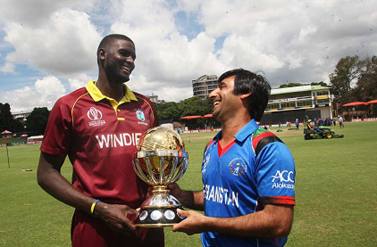 Playing for Keeps! West Indies captain Jason Holder (left) shares a laugh with Afghanistan skipper Asghar Stanikzai while posing with the tournament trophy, ahead of today’s final. (Photo courtesy ICC Media)