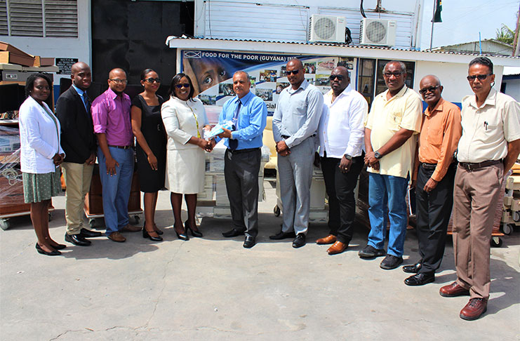 Chief Executive Officer, Food For the Poor Inc, Kent Vincent (centre) presents tokens of donation to Minister within the Ministry of Public Health, Dr Karen Cummings at the handing-over ceremony at FFP.  Looking on are Health and Food for the Poor Inc officials.