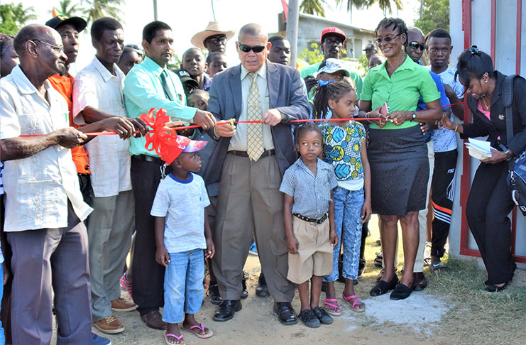 Minister of Social Cohesion with responsibility for Youth, Culture and Sport, Dr George Norton, is assisted by residents and regional officials as he cuts the ribbon to commission the recently-rehabilitated Paradise Sports Club ground.