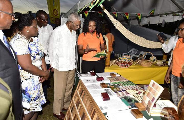 President David Granger examines a locally made cup, as LCICD’s Victor Fernandes and Member of Parliament Jermaine Figueira (third and second right respectively) look on appreciatively during the opening of the expo on Friday.