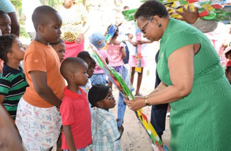 Minister of Public Health Volda Lawrence gives a kite to this little one during the distribution exercise on Friday