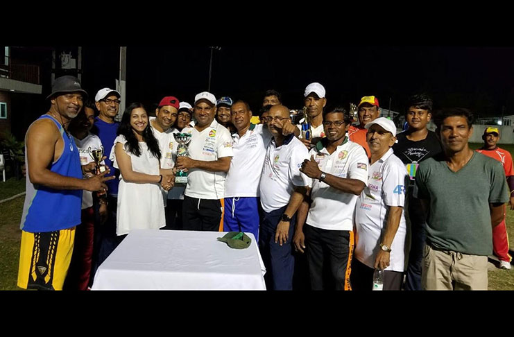 Bibi Sangster of the USA handed over the winning trophy to captain Ricky Deonarain in the presence of the smiling birthday boy and others