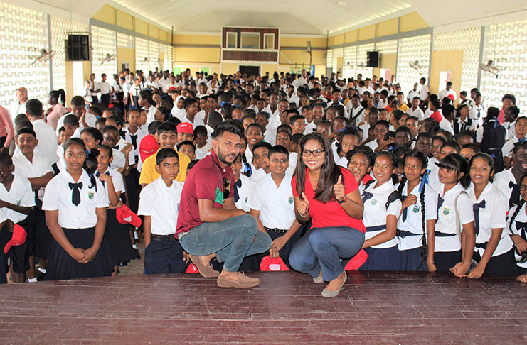 Devendra Bishoo poses with schoolchildren who were recipients of Digicel branded caps.