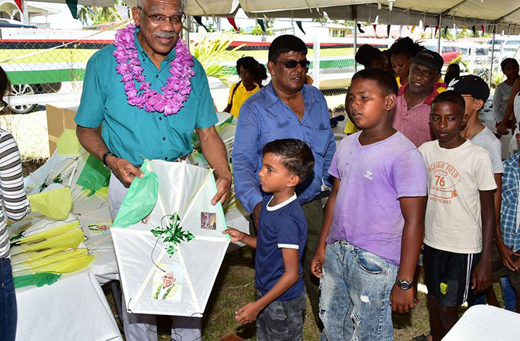 President David Granger gives a kite to this lad during a stop at the Original Market Square, Bath Settlement, West Coast Berbice, where he was welcomed by a large crowd