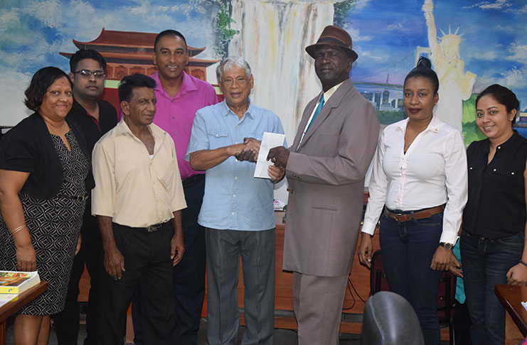 In photo, PRO Guy Griffith (with hat) receives cheque from Robert Hanoman, while the president Aleem Hussain (4th from left) and some of the agency’s staff enjoy the moment of goodwill. (Picture - compliments of Kaieteur News)
