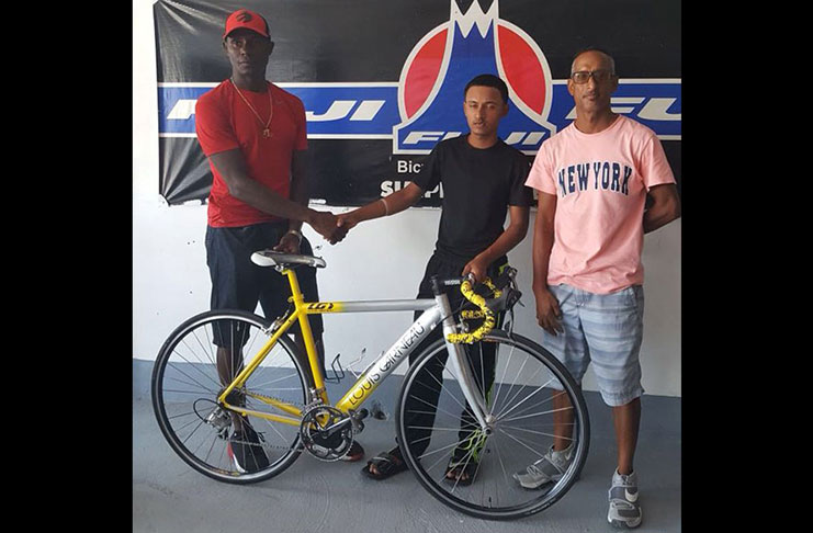 Former national cyclist Wilbert Benjamin (left) presents a new racing cycle to the promising Berbice cyclist Chameshwar `Satesh’ Dhanai (centre) recently.