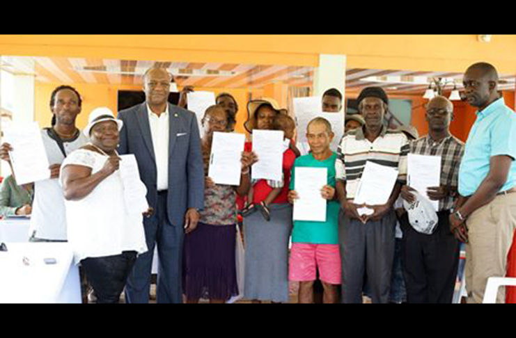 Minister of State Joseph Harmon with some of the residents who received titles for their lands