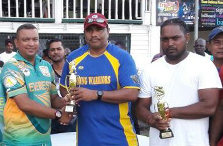 Everest Masters captain Rajesh Singh (left) collects the winners’ trophy from his opposite number, Anil Beharry, in the presence of man-of-the-match Saheed Mohamed (right).