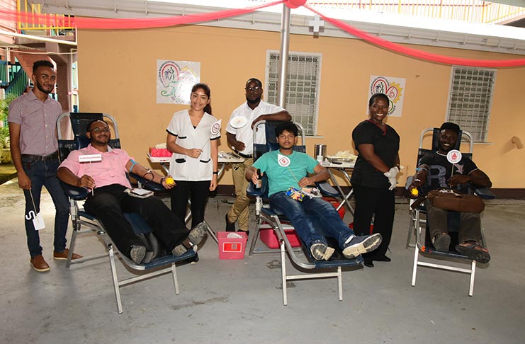 Three young men in the process of donating blood at the Ptolemy Reid Rehabilitation Centre, in observance of Rehabilitation Week 2018. Looking on are members of the centre and the National Blood Transfusion Service. (Adrian Narine photo)