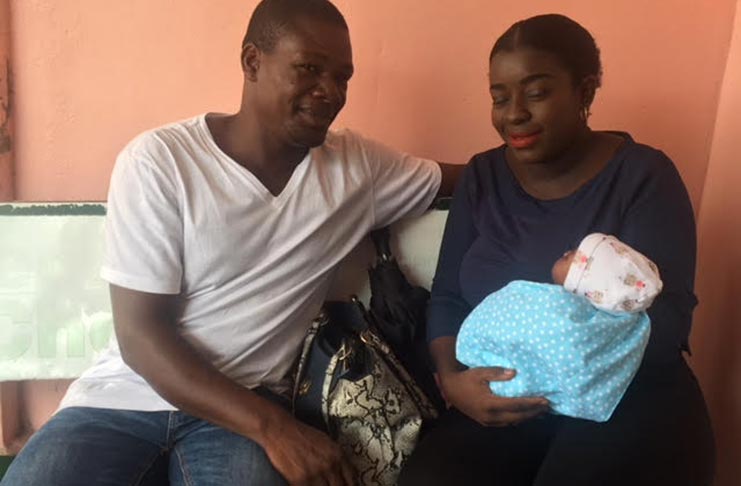 A father with his wife and newborn baby, awaiting the taxi to take them home from the Georgetown Public Hospital Corporation ( GPHC)