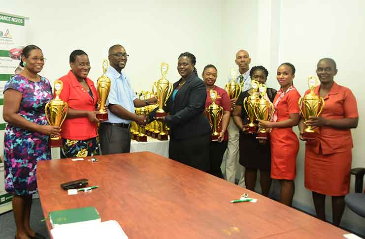 GTU President Mark Lyte (third left) accepts the donated trophies from Assuria’s Eulalie Wilson (Photo by Adrian Narine)