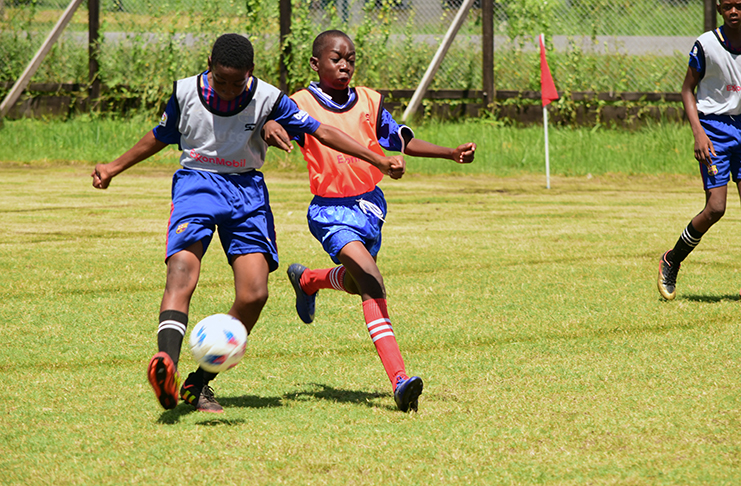 A hustle for the ball! These two players jostle for possession last week in the ExxonMobil U-14 football tournament, which continues this weekend. (Adrian Narine photo)