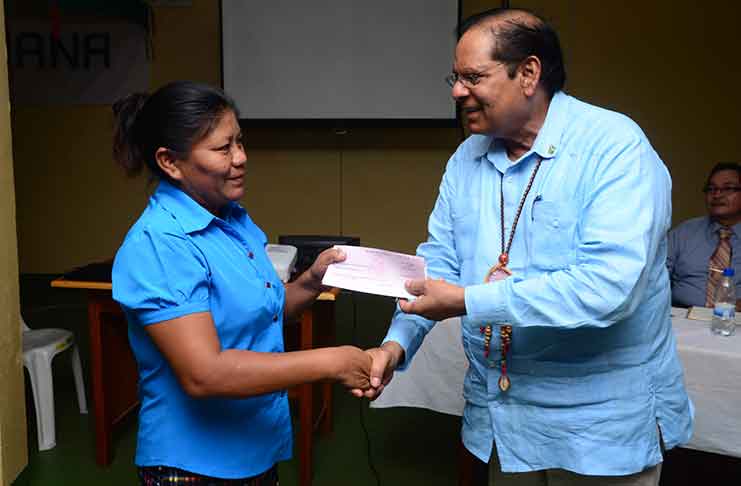 Prime Minister Moses Nagamootoo (right) presents a cheque to a female village leader on Thursday during the opening of the Regional Toshaos’ Conference. (Delano Williams photo)