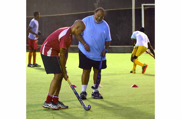 FIH coach Shiv Jagday guides a player through his paces on the artificial turf, at GCC. (Adrian Narine photo)