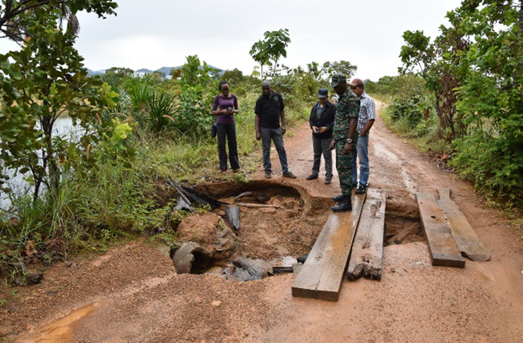 Director-General of the Civil Defence Commission (CDC), Lieutenant-Colonel Kester Craig and other officers examine a damaged section of the roadway.