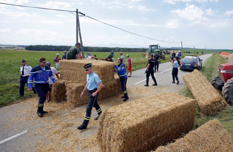 Police officers remove hay bales off the road after a protest. (REUTERS/Stephane Mahe)
