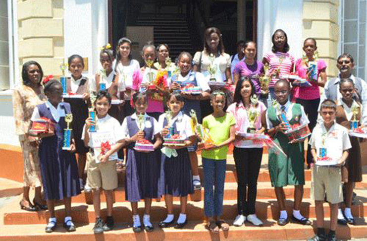 School children posing on the stairs of the Georgetown National Library, showing off
their trophies and other prizes received for work well done