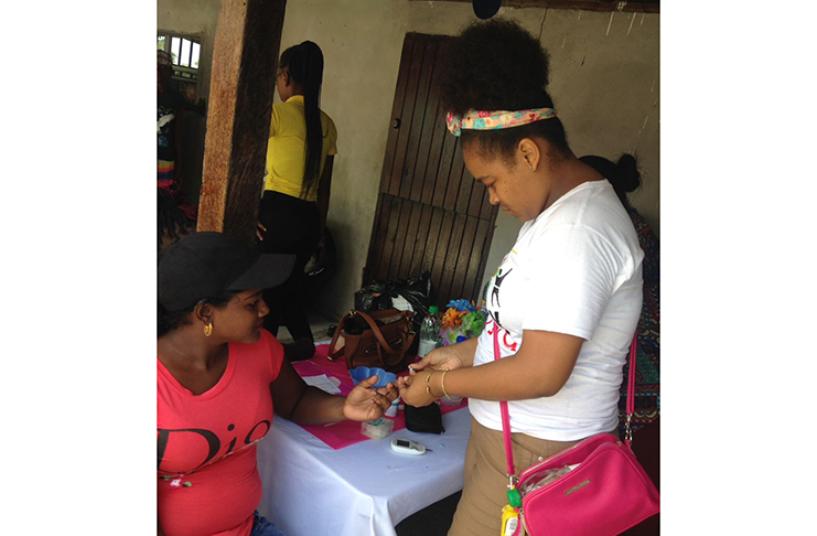 A health volunteer attends to a member of the Andyville community in Linden