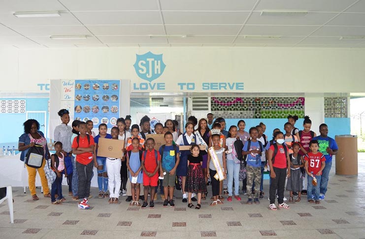 Members of Give Another Chance Foundation posing with top performers who excelled at the NGSA and were gifted backpacks and laptops on Wednesday